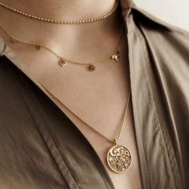 Woman wearing multiple gold-tone necklaces.