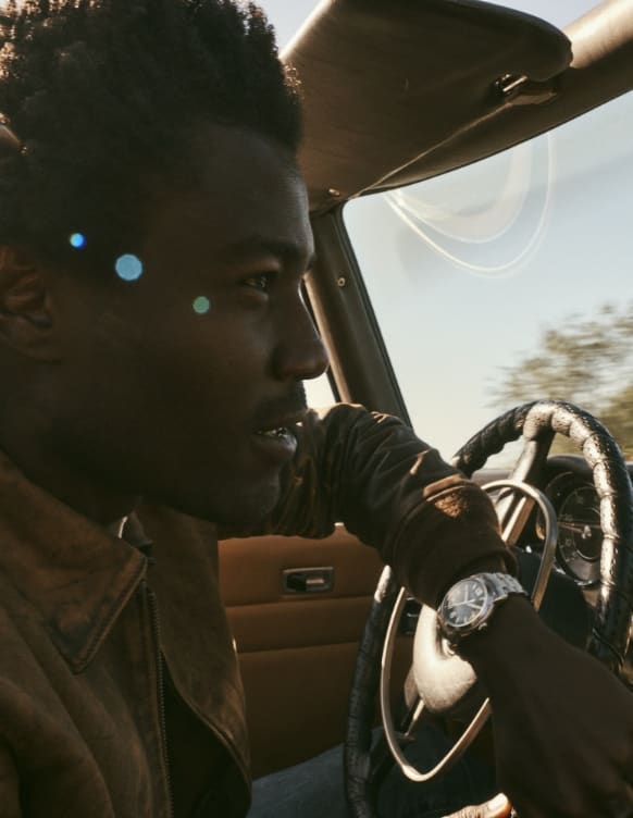 Hombre conduciendo un coche con un reloj Fossil Heritage.