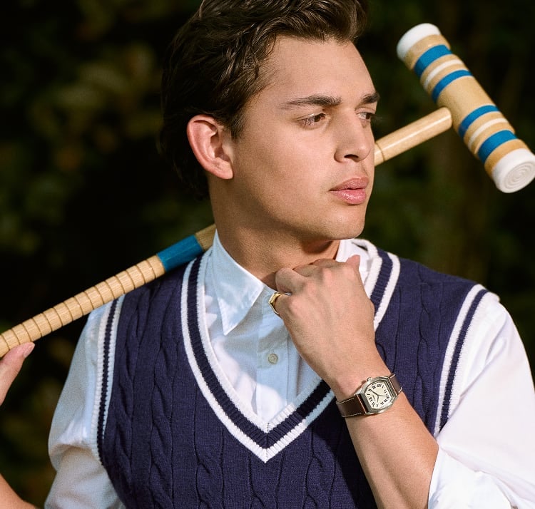 A man dressed in a sweater vest, holding a croquet mallet and the Fossil Harlow 33mm watch.