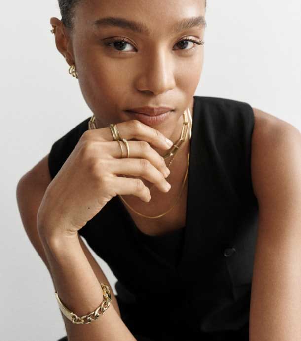 A woman wearing the Harlow Linear jewelry collection. Closeup of the gold-tone Harlow Linear jewelry collection.