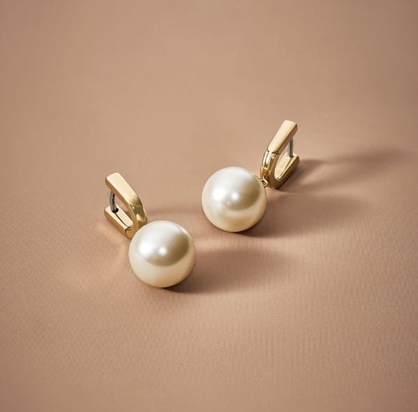 Des boucles d’oreilles en fausses perles de verre et dorées.