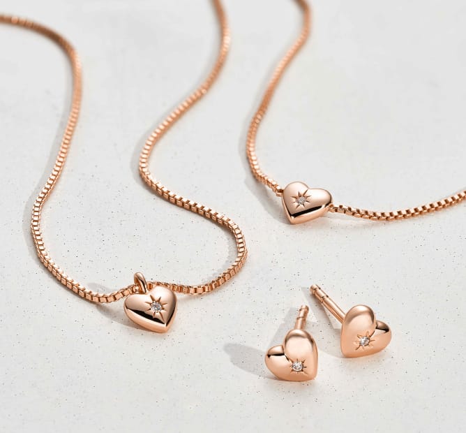 Two gold-tone, heart-shaped pendant necklaces engraved with an X and an O.