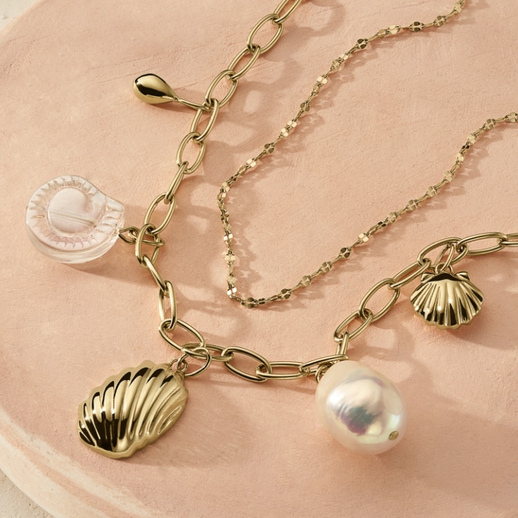 Bijoux dorés pour femme avec des perles de culture d’eau douce baroques et des motifs de coquillages.