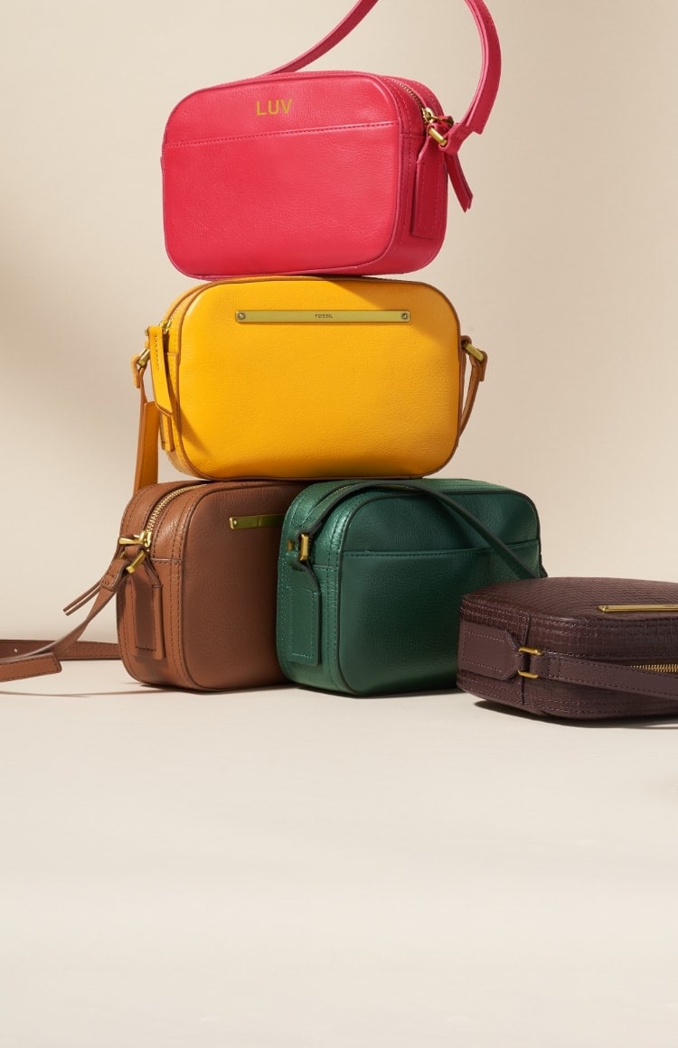 A woman carrying a brown leather Liza camera bag and five Liza camera bags in green, yellow, red, blue and brown.