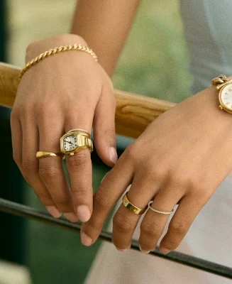 A lifestyle image of a woman wearing a gold-tone watch ring with a round case.