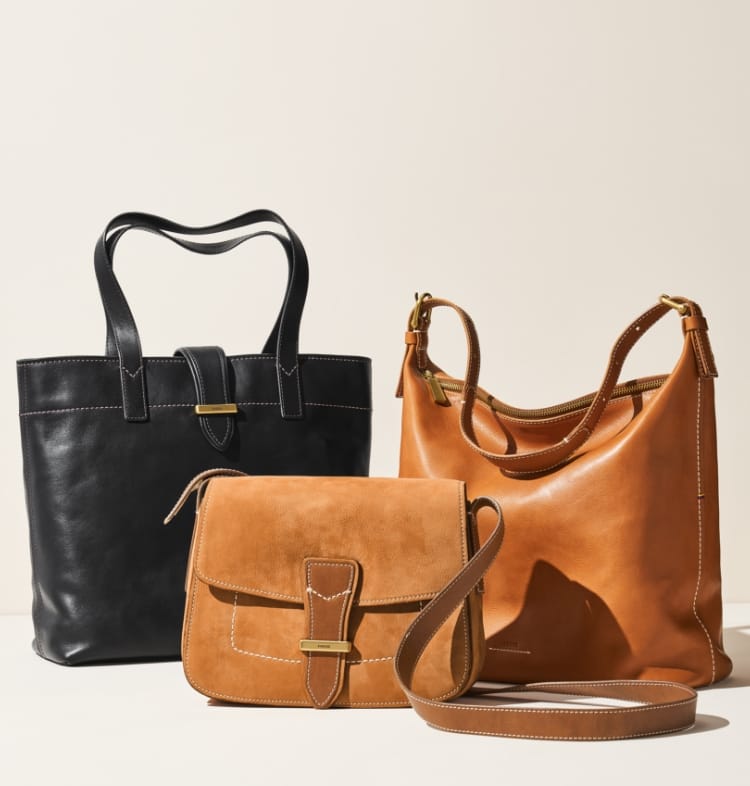 Black leather, brown suede and brown leather Tremont bags on a cream background.