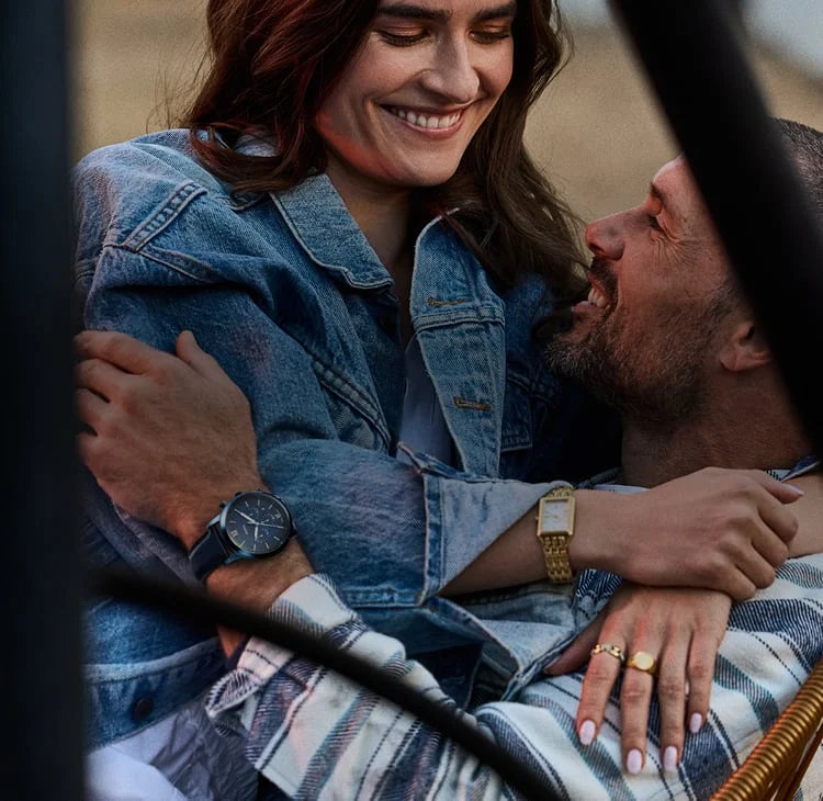 A husband and wife embracing on the beach. He's wearing the Fossil Neutra chronograph watch.