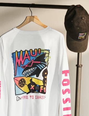 Maui and Sons x Fossil shirt with a shark graphic. A Maui and Sons hat hanging on a clothing rack.