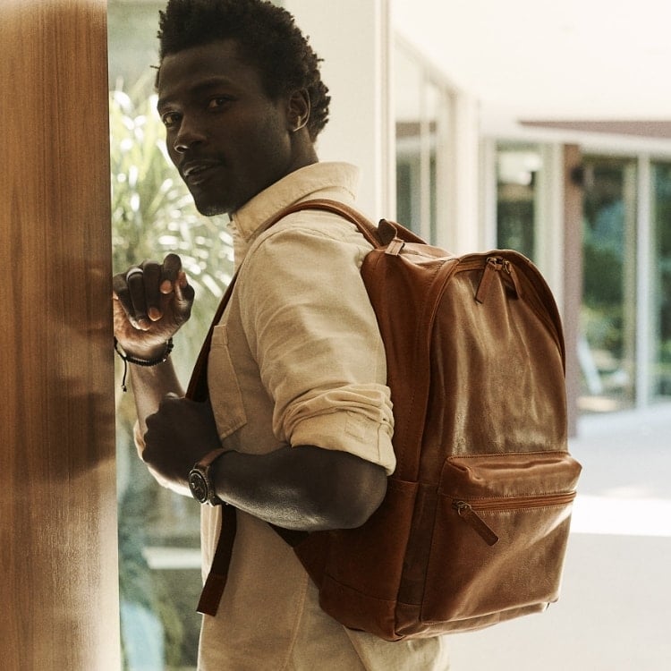 A man wearing the brown leather Buckner backpack.