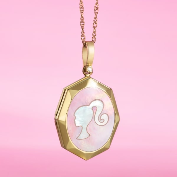 A pink background with our limited edition Barbie™ x Fossil gold-tone locket featuring mother-of-pearl embellishments, a gold-tone stainless steel chain with a lobster clasp and finished with a stylish Barbie silhouette.