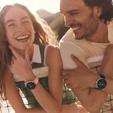 Ein lachender Mann und eine lachende Frau mit Fossil Smartwatches. 