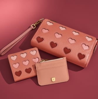Three pink leather wallets, two of which have heart details.