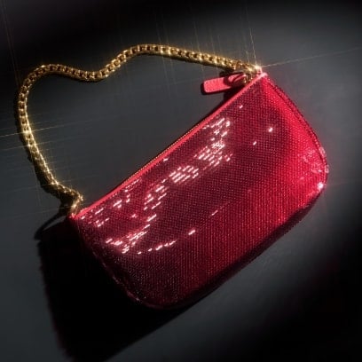 Une pochette rouge à paillettes avec un bracelet chaîne doré.
