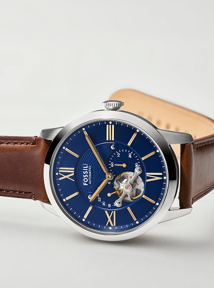 A side-by-side view of a man carrying a surfboard while wearing the Fossil Townsman Automatic, shown alongside a detailed image of the same watch.