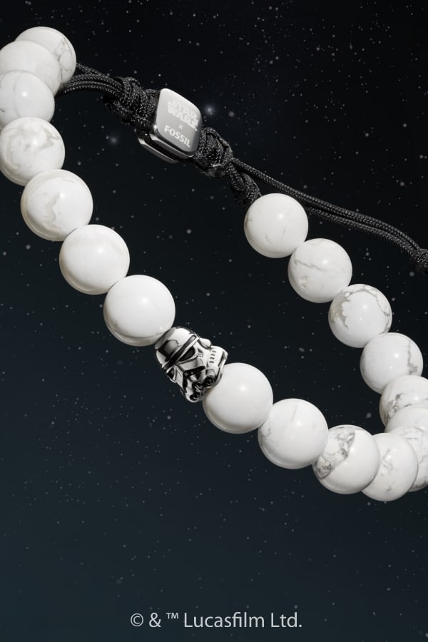 Un bracelet de perles blanches avec une perle représentant un casque de stormtrooper