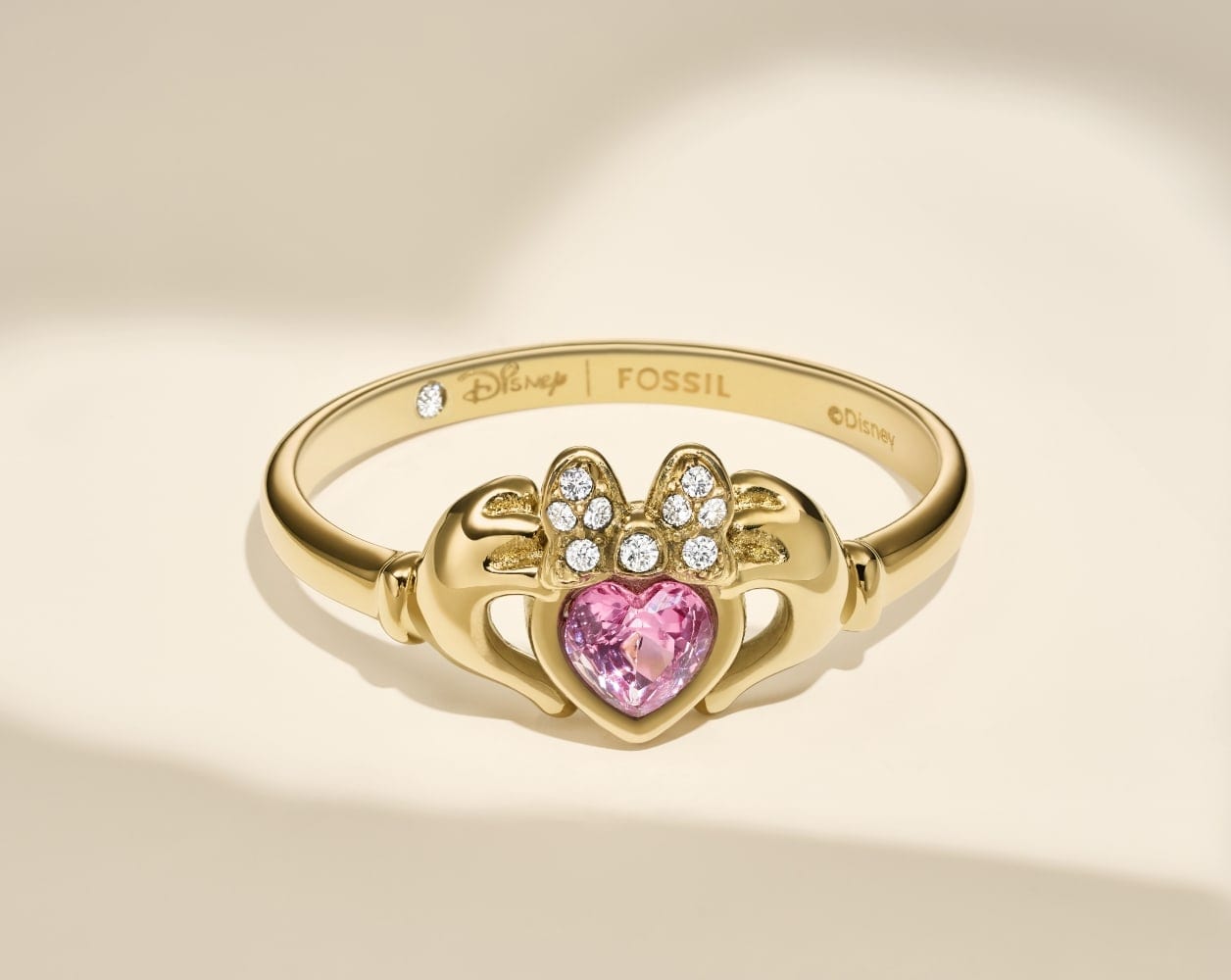 The gold-tone Disney | Fossil Claddagh ring with a pink, heart-shaped crystal.