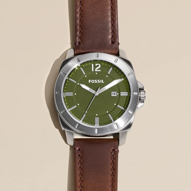 un gros plan d’une montre pour homme classique au cadran vert olive et au bracelet en cuir marron.