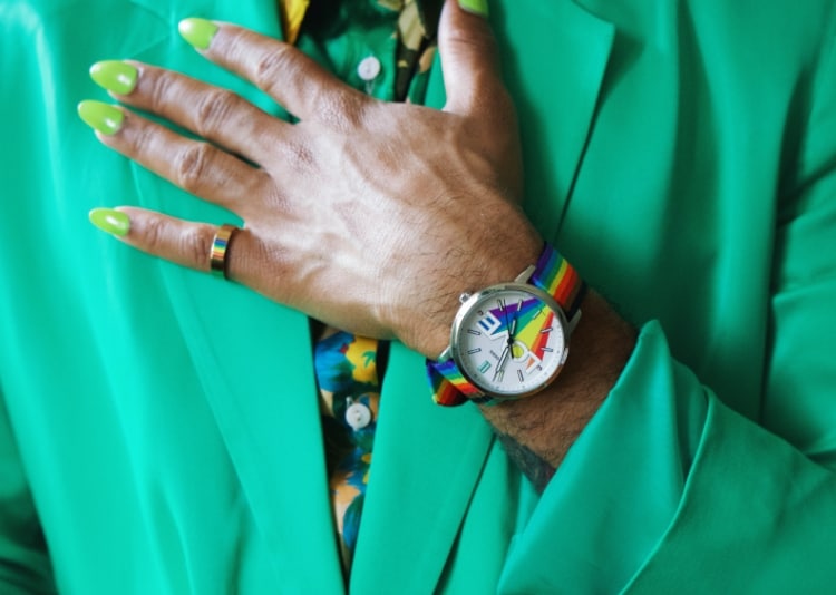 Person in einem grünen Anzug, die eine Fossil Pride Uhr trägt.