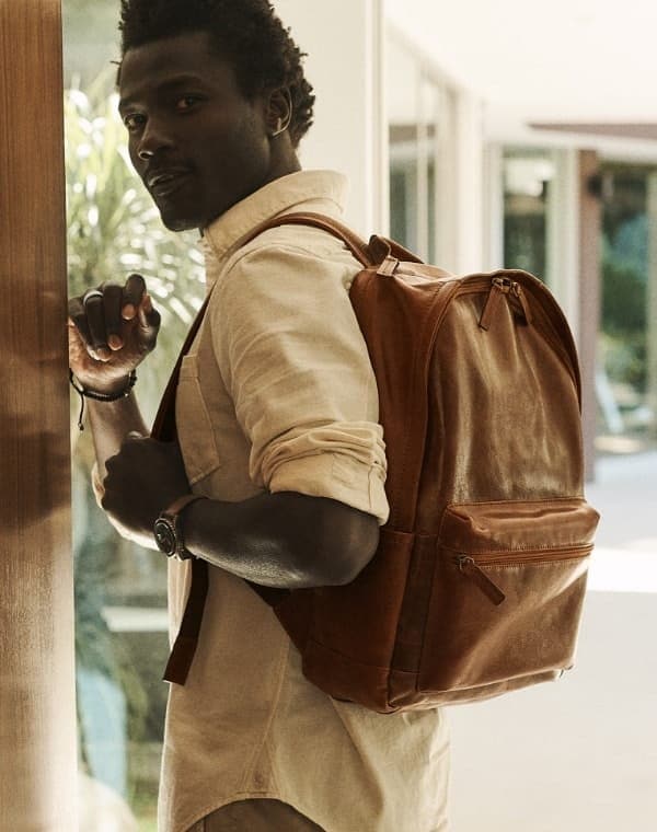 A man carrying the brown leather Buckner backpack.