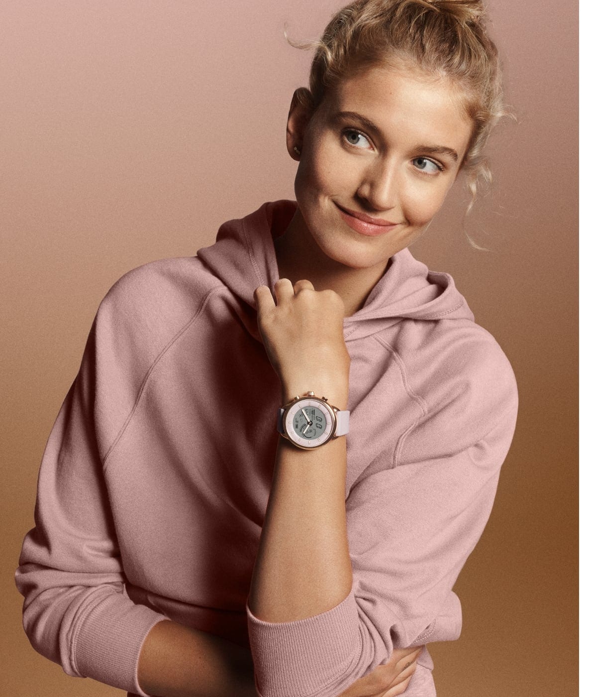 Une femme portant un sweat rose et une montre connectée hybride Gen 6 édition Wellness.