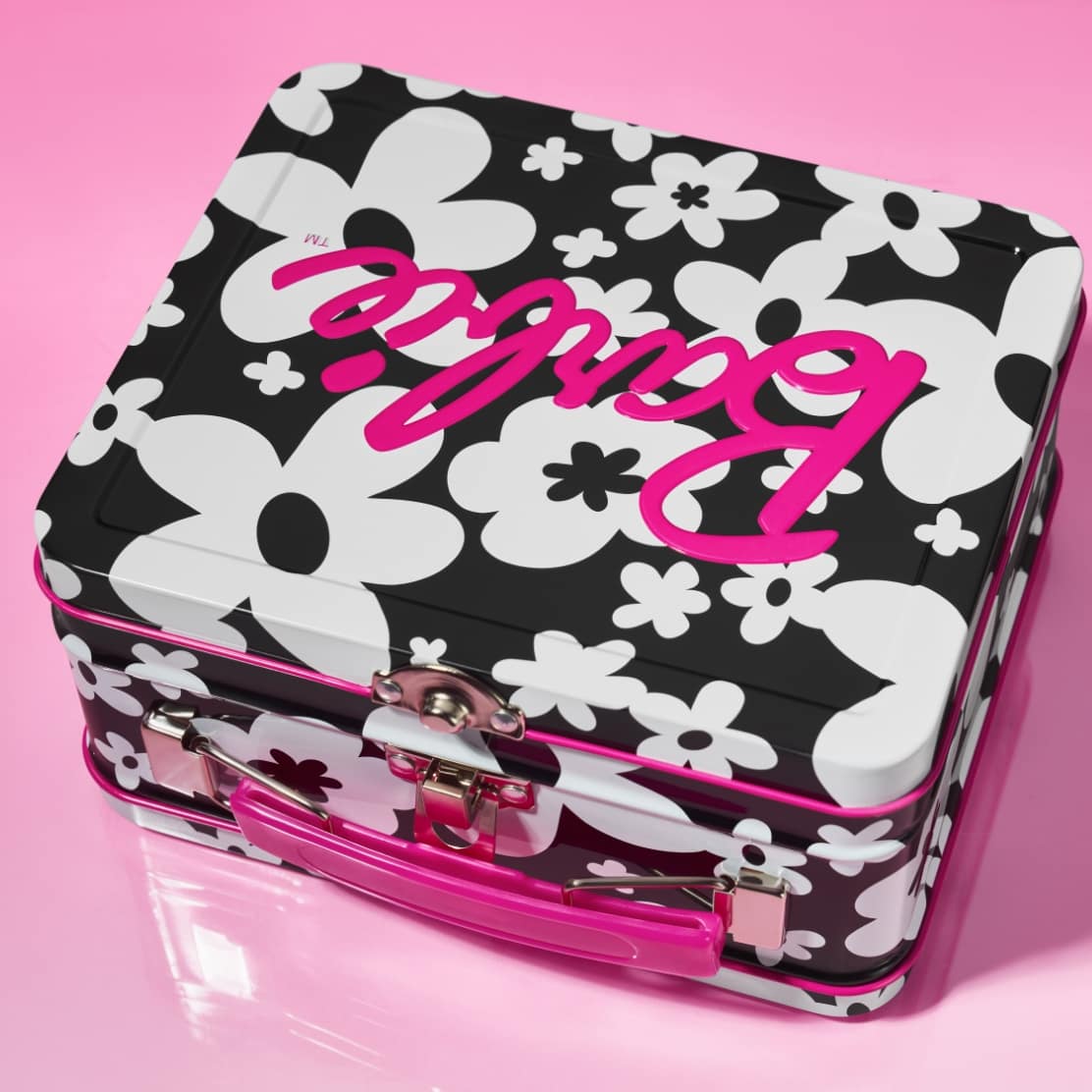 Image one. A lunchbox-inspired Barbie tin featuring a graphic black-and-white floral print with hot pink accents.