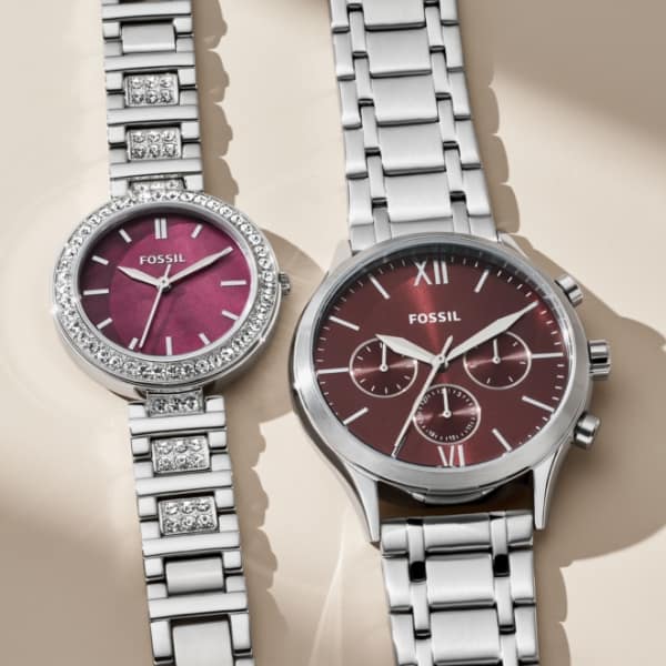 A gift set featuring a men’s and women’s watch. Both styles are accented with a burgundy dial in a stainless steel case.