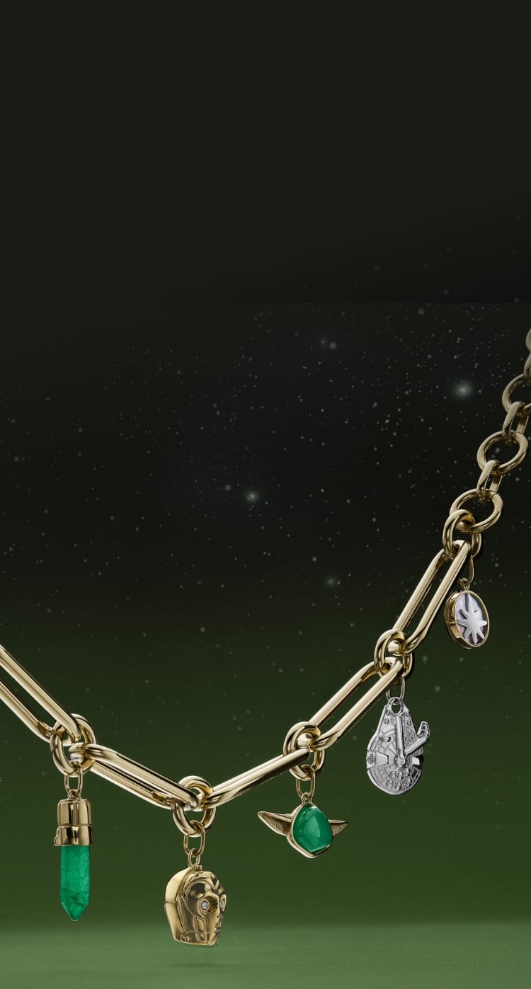 Ein goldfarbenes Armband mit Charmanhängern in Form von Yoda, des Millennium Falken, C-3PO, R2-D2 und einem Lichtschwert.