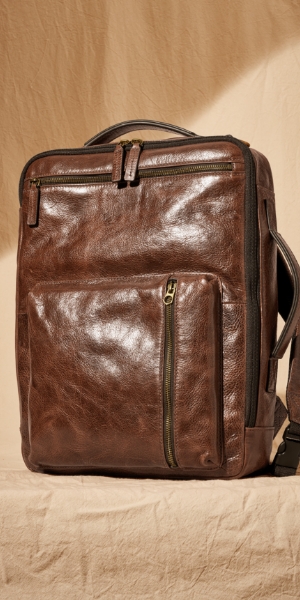 Man standing near a car with the brown leather Buckner backpack.