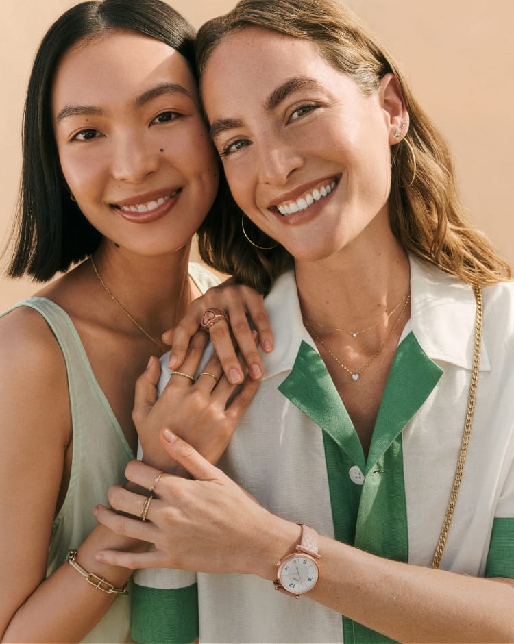 Two women hugging and wearing Fossil jewellery.
