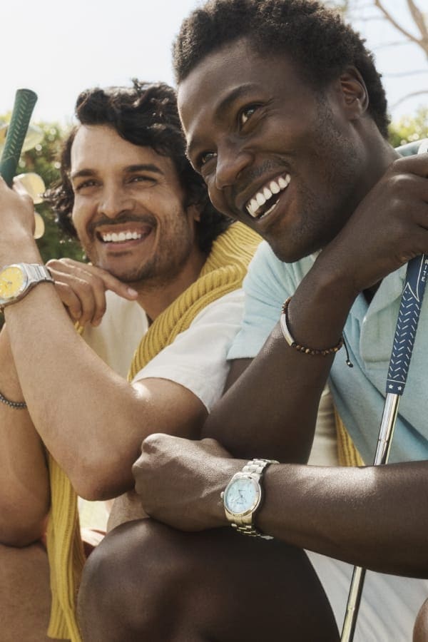 Two men smiling and wearing Fossil watches with colourful dials. 