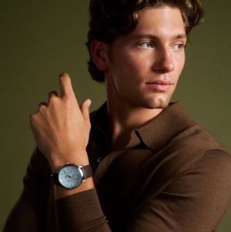 A man wearing a watch with an icy blue dial. 
