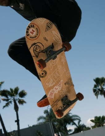 A man doing a trick on a Madrid x Fossil skateboard with exclusive Fossil graphics.