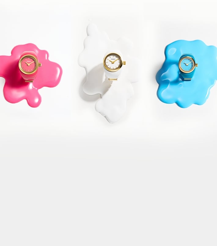 Four watch rings resting on splashes of paint in black, pink, white, and blue