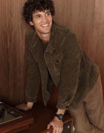 Un homme souriant et s’appuyant sur une table. 