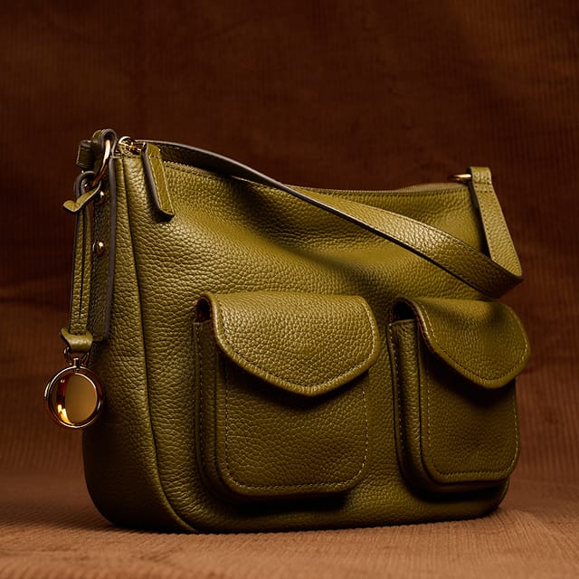 An olive green leather shoulder bag with two front utility pockets.