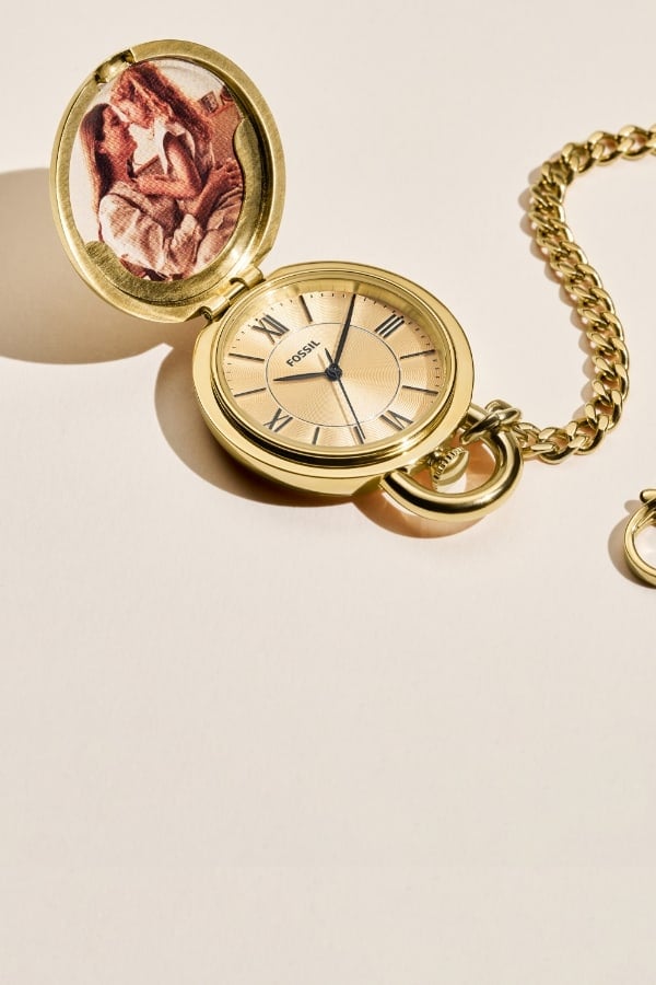 Une montre gousset Fossil dorée, qui s’ouvre pour dévoiler une photo à l’intérieur et un cadran doré.
