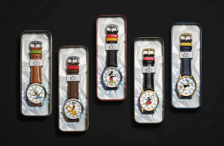 A GIF image featuring collectible tins for each of the five character watches celebrating the Mickey and friends characters. Shown from left to right: Goofy, Pluto, Mickey Mouse, Minnie Mouse and Donald Duck. The second image shows a group shot of the five anniversary watches. The D100 logo is featured beneath, celebrating Disney's 100th anniversary, followed by the Disney and Fossil logo lockup.