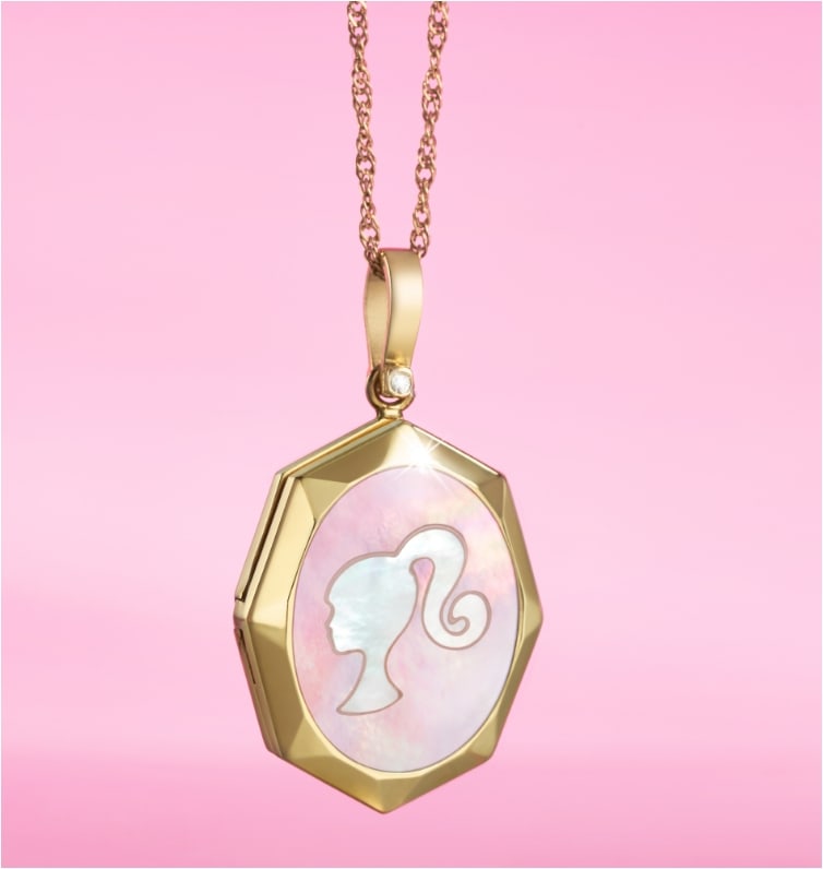 A pink background with our limited edition Barbie™ x Fossil gold-tone locket featuring mother-of-pearl embellishments, a gold-tone stainless steel chain with a lobster clasp and finished with a stylish Barbie silhouette.
