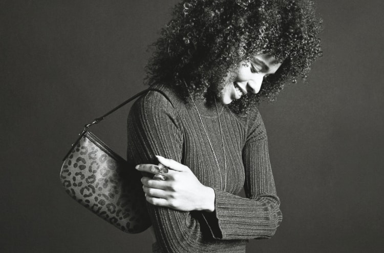 Black-and-white image of a woman carrying the leopard print Jolie handbag.