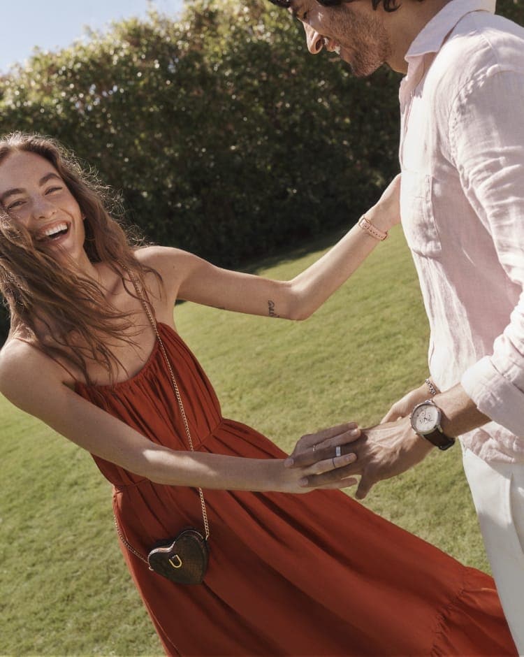 A woman in a red dress dancing with a man in a white shirt, while wearing Fossil accessories.
