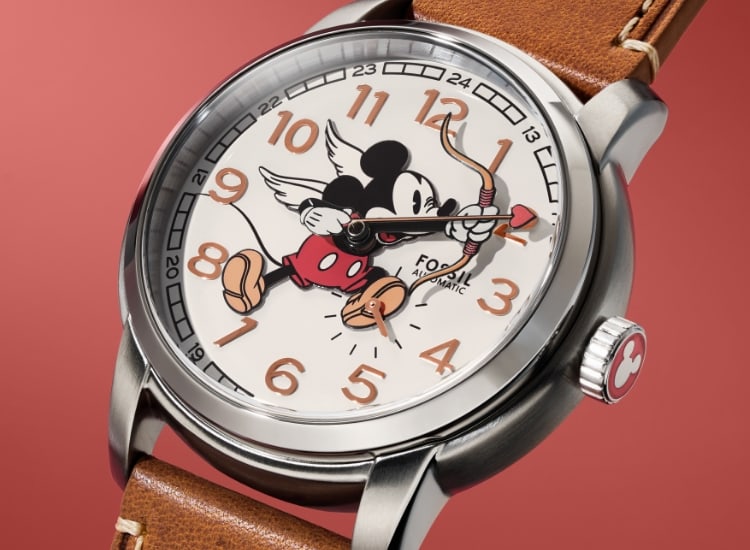 Die Uhr Fossil Heritage mit braunem Lederband und Micky Maus als Amor auf dem Zifferblatt.