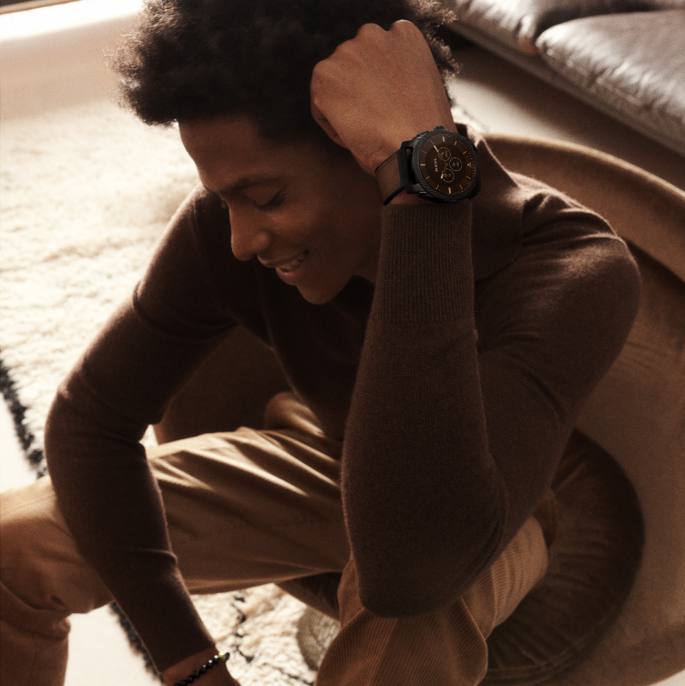A man lounging in a chair wearing a black watch.