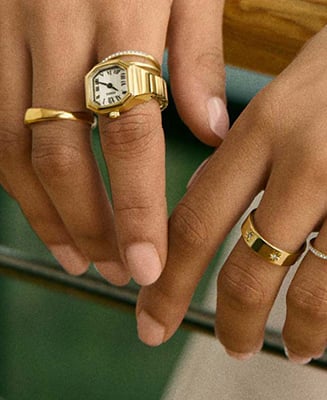 A lifestyle image of a woman wearing a gold-tone watch ring with a round case.