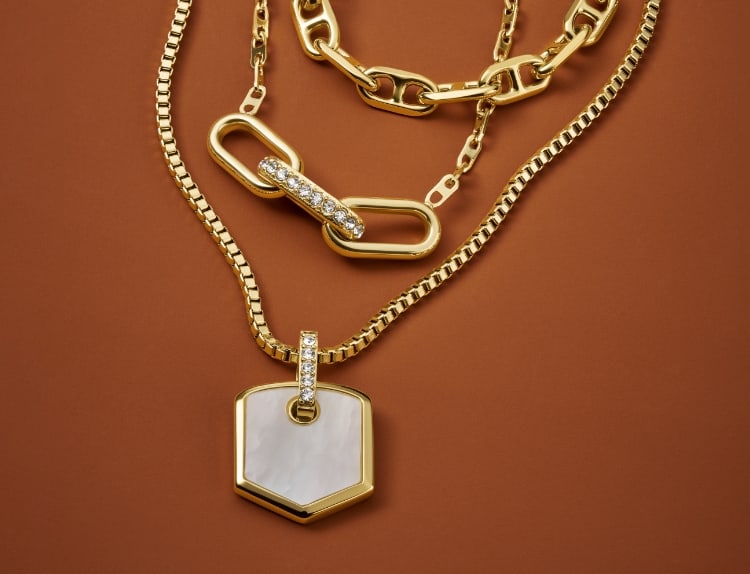 Three gold-tone Fossil Heritage Jewelry necklaces, featuring mother-of-pearl and crystal accents.