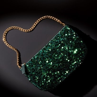 Une pochette vert émeraude à paillettes avec un bracelet chaîne doré.