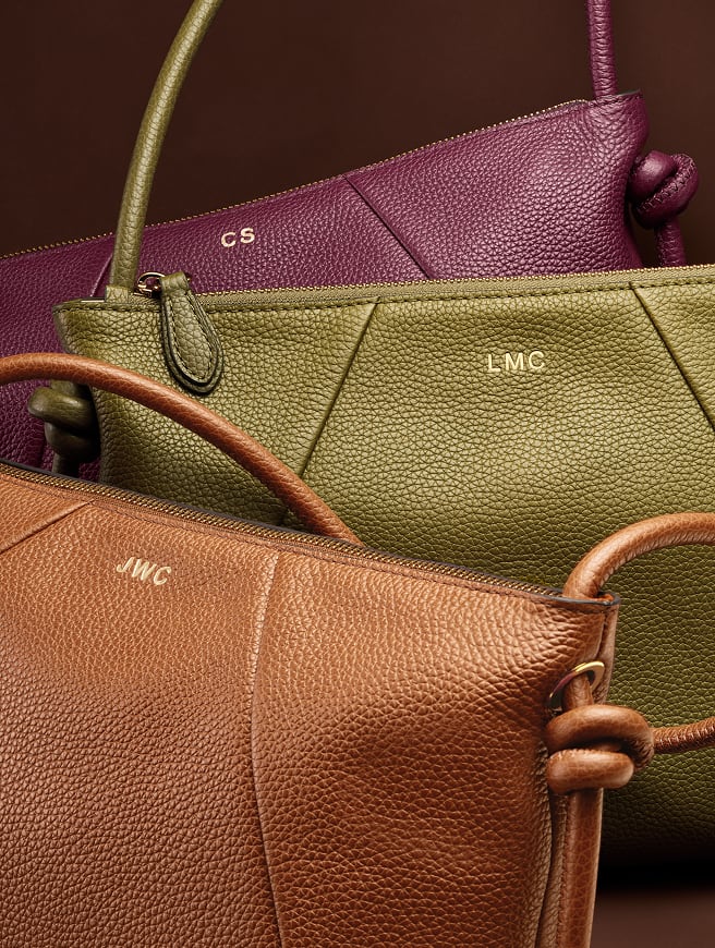 The Willa bag, a relaxed silhouette crafted of pebbled leather, shown in rich shades of brown, olive and berry with custom embossing.
