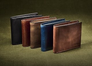 A lineup of five leather bifold wallets in shades of black, brown and blue.