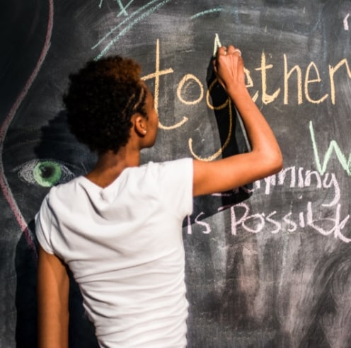 A young boy writing on a chalkboard.