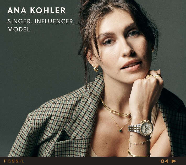 Ana Kohler pose souriante et porte de nombreux bijoux dorés de la collection d'automne Fossil. 