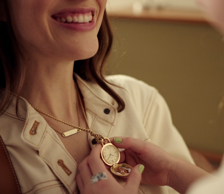 A child opens her mother's Fossil Watch Locket, revealing a picture of the two of them.